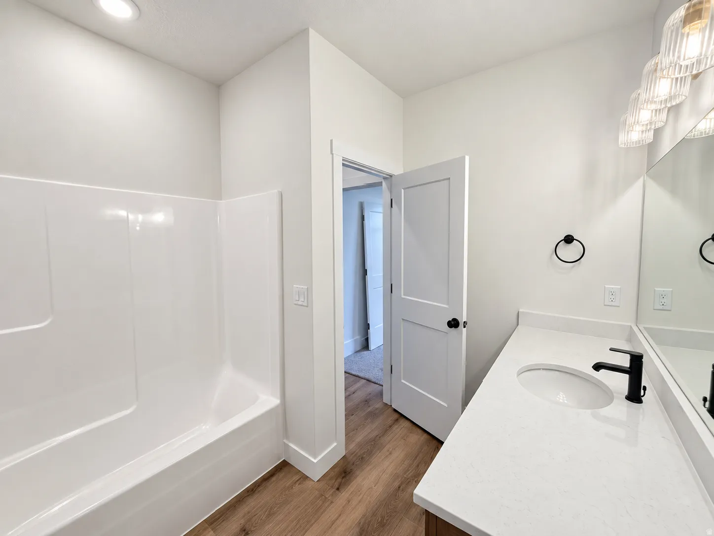 Wood-finish flooring with a white vanity featuring a rectangular under-mount sink