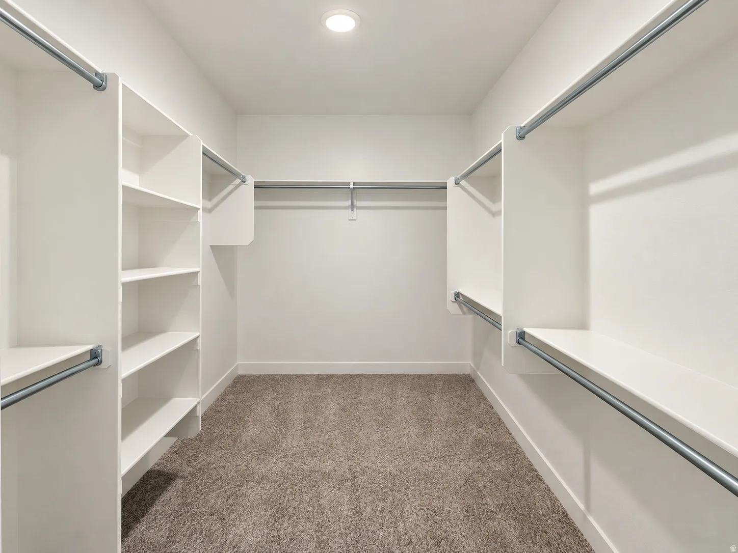 Walk-in closet featuring built-in shelving, multiple hanging rods, and recessed lighting