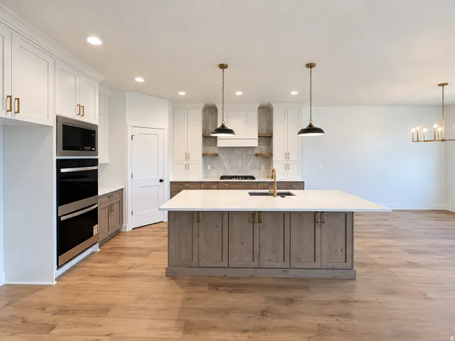 Kitchen featuring a large island with a surface, wood-finish flooring, built-in stainless steel appliances, white cabinetry, and recessed lighting