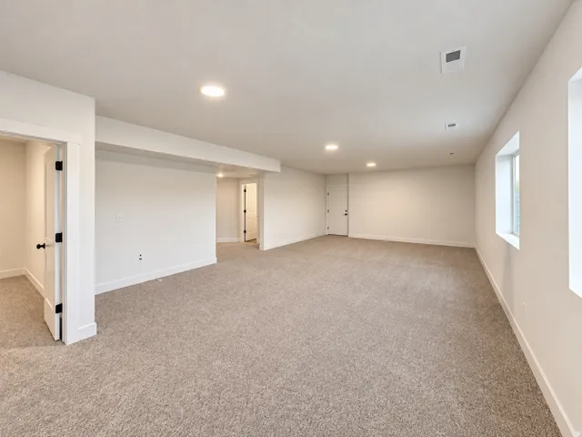 Spacious interior featuring recessed lighting, light-toned carpeting, white walls, and multiple windows with white trim