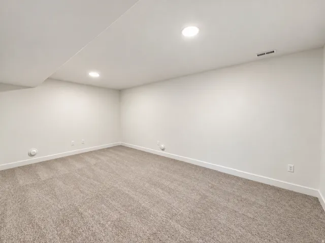 Recessed lighting illuminates the carpeted flooring and light-toned walls