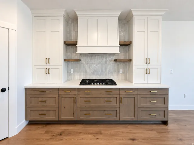 Built-in white cabinetry, wood-finish lower cabinetry, built-in gas cooktop, light-toned countertop, and wood-finish flooring