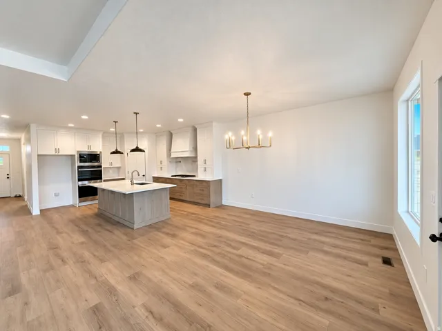 Open-concept living space with wood-finish flooring, recessed lighting, and a modern chandelier