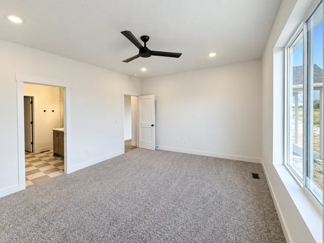 Expansive room with neutral carpet, recessed lighting, and a modern ceiling fan