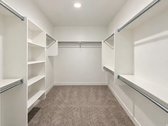 Walk-in closet featuring built-in shelving, multiple hanging rods, and recessed lighting