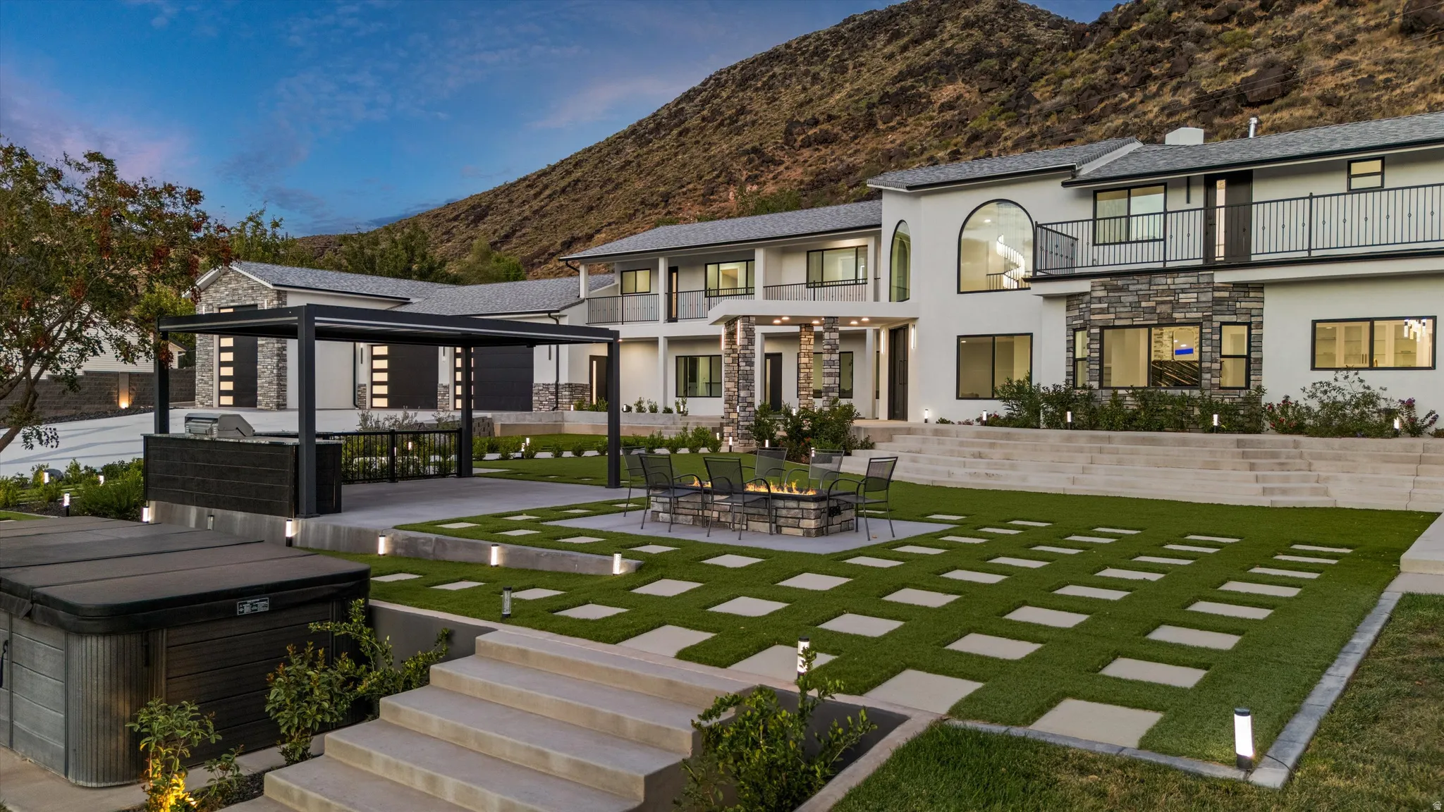 Expansive outdoor living area featuring a built-in fire pit, artificial turf with paver accents, and a covered outdoor kitchen