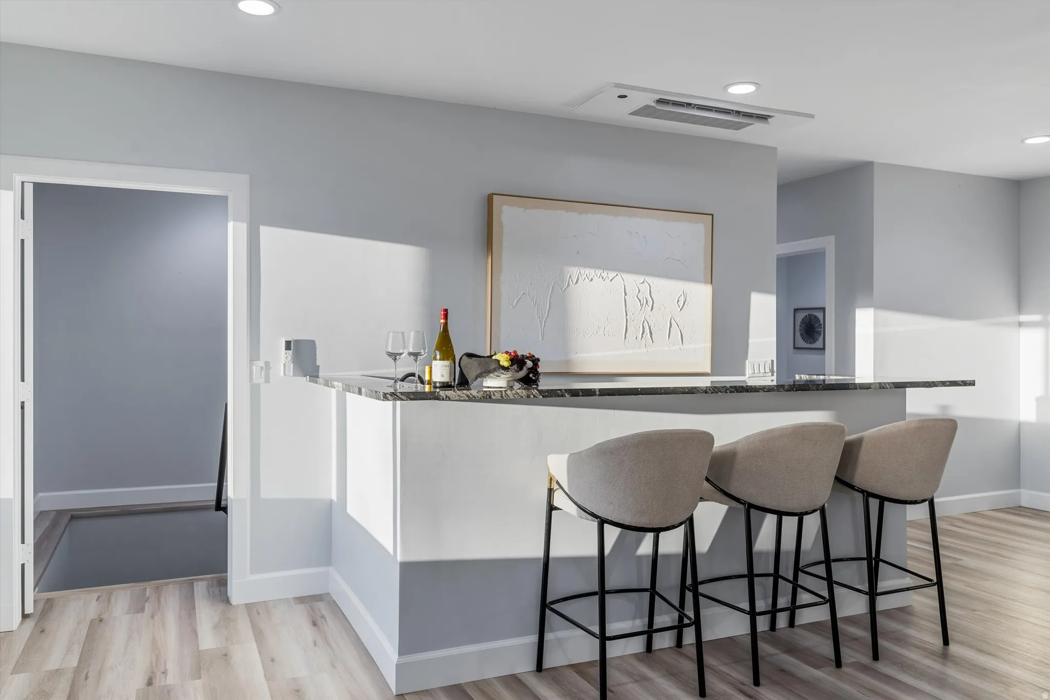 Breakfast bar with a stone-finish countertop, wood-finish flooring, and recessed ceiling lighting