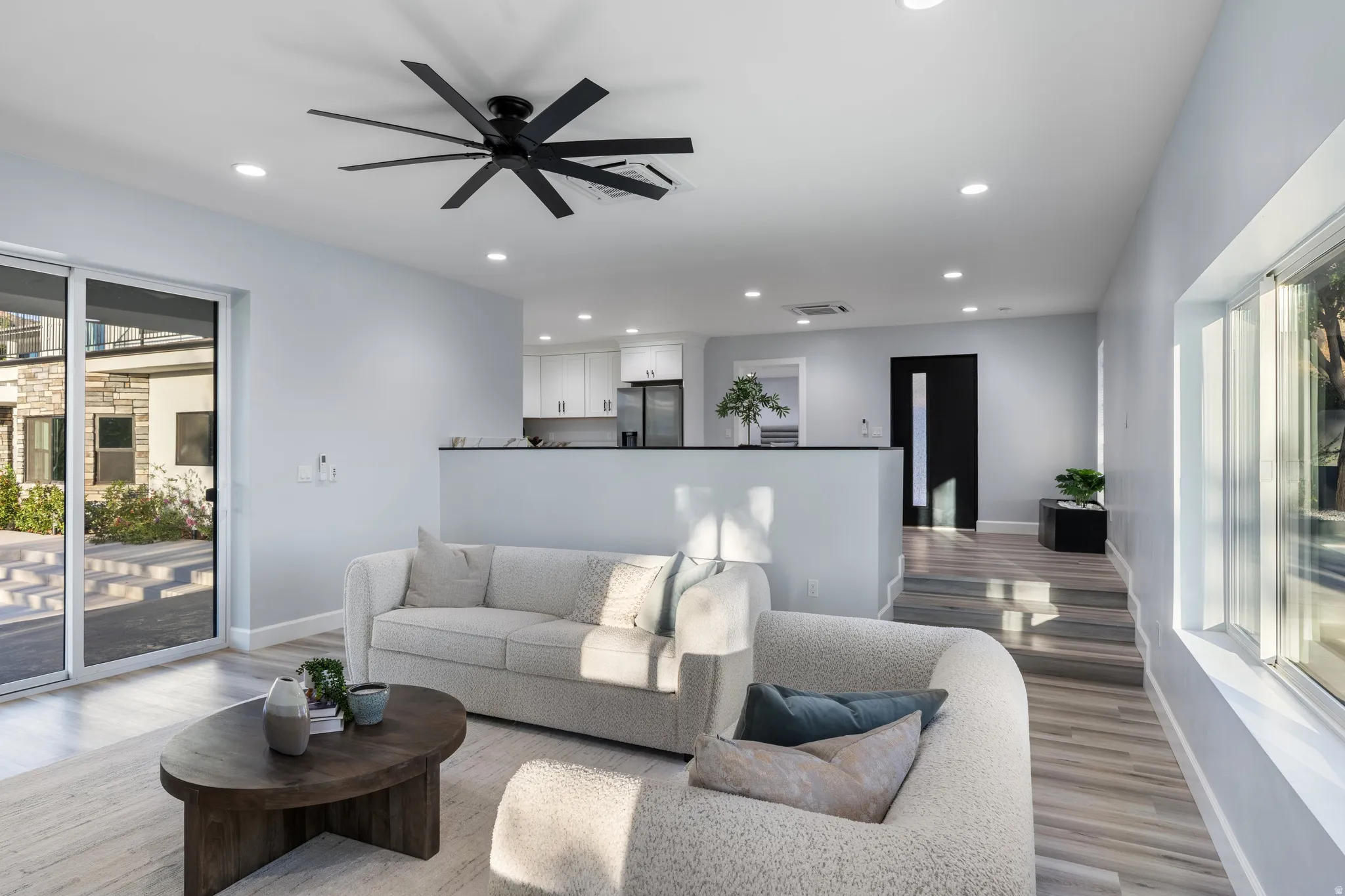 Spacious living area with wood-finish flooring, recessed lighting, and a modern ceiling fan