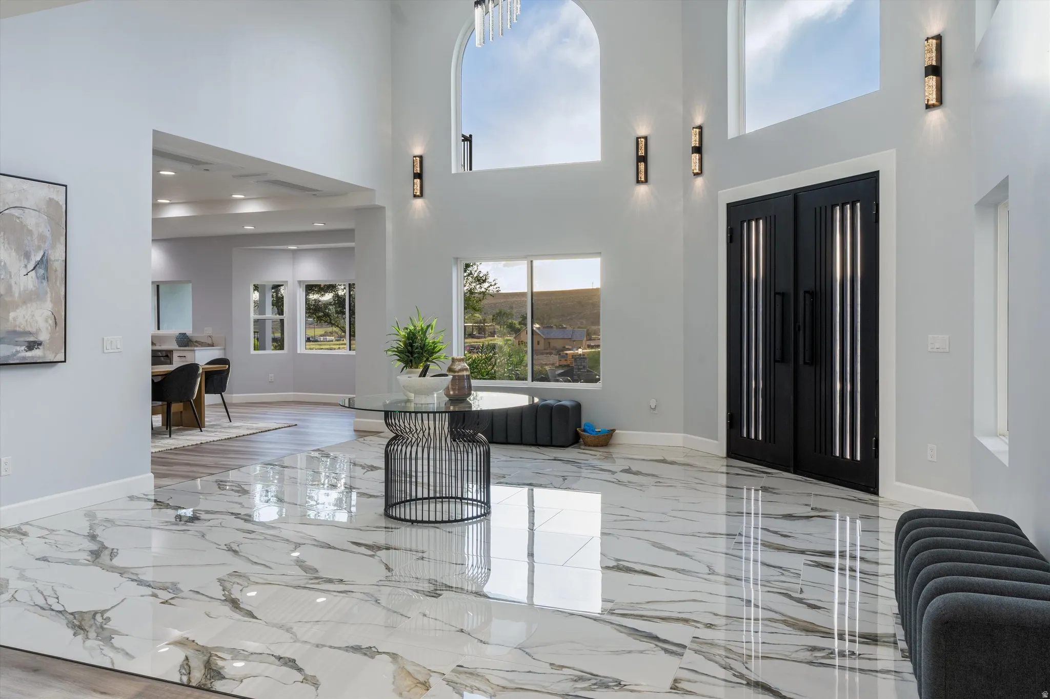 Two-story entry foyer featuring large-format tile flooring, a double-height arched window, and double black entry doors
