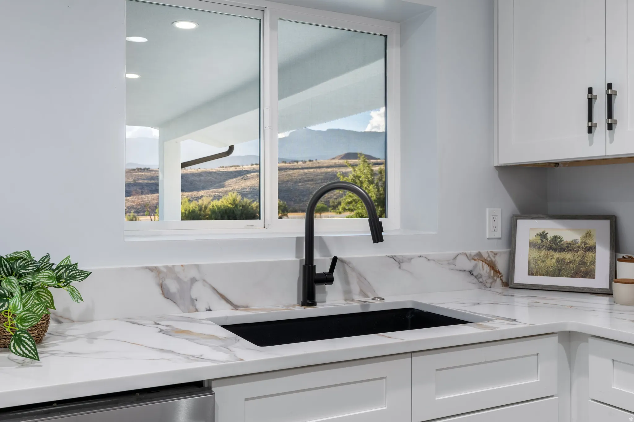White shaker-style cabinetry with matte black hardware, white countertop with veining, single-basin black sink, and matte black faucet