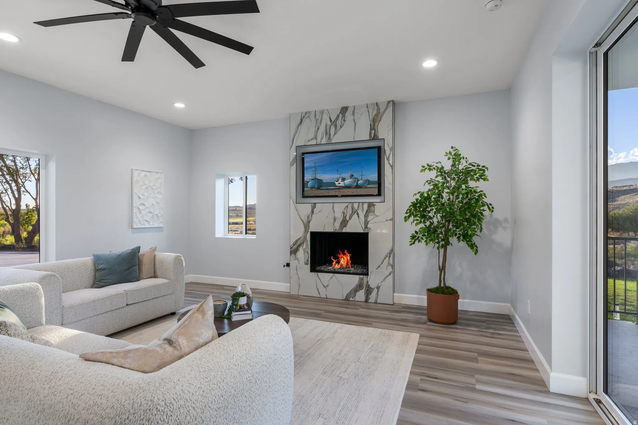 Modern fireplace with a natural stone surround, recessed lighting, wood-finish flooring, and a large sliding glass door