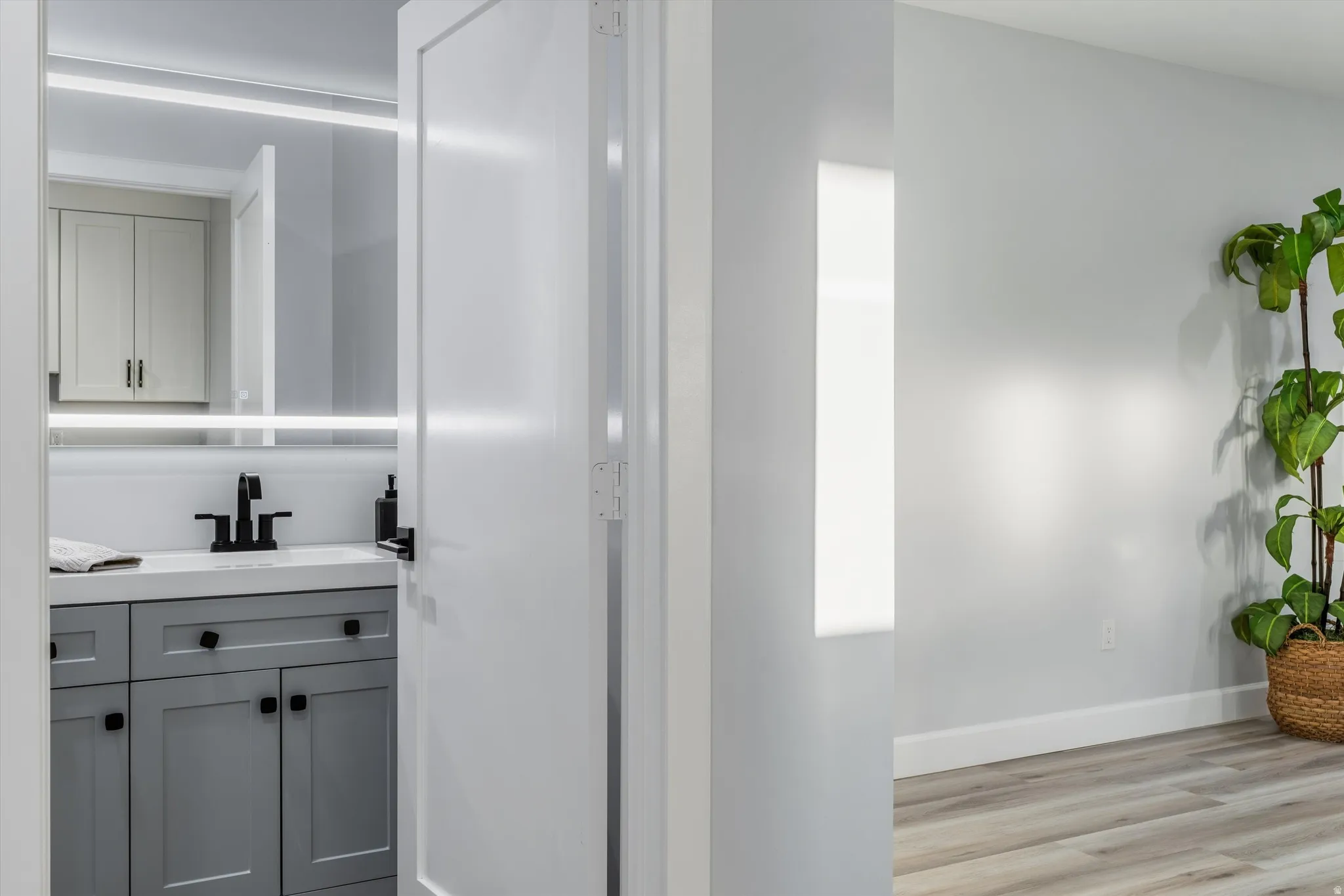 Bathroom vanity with gray shaker cabinetry, white countertop, and black fixtures
