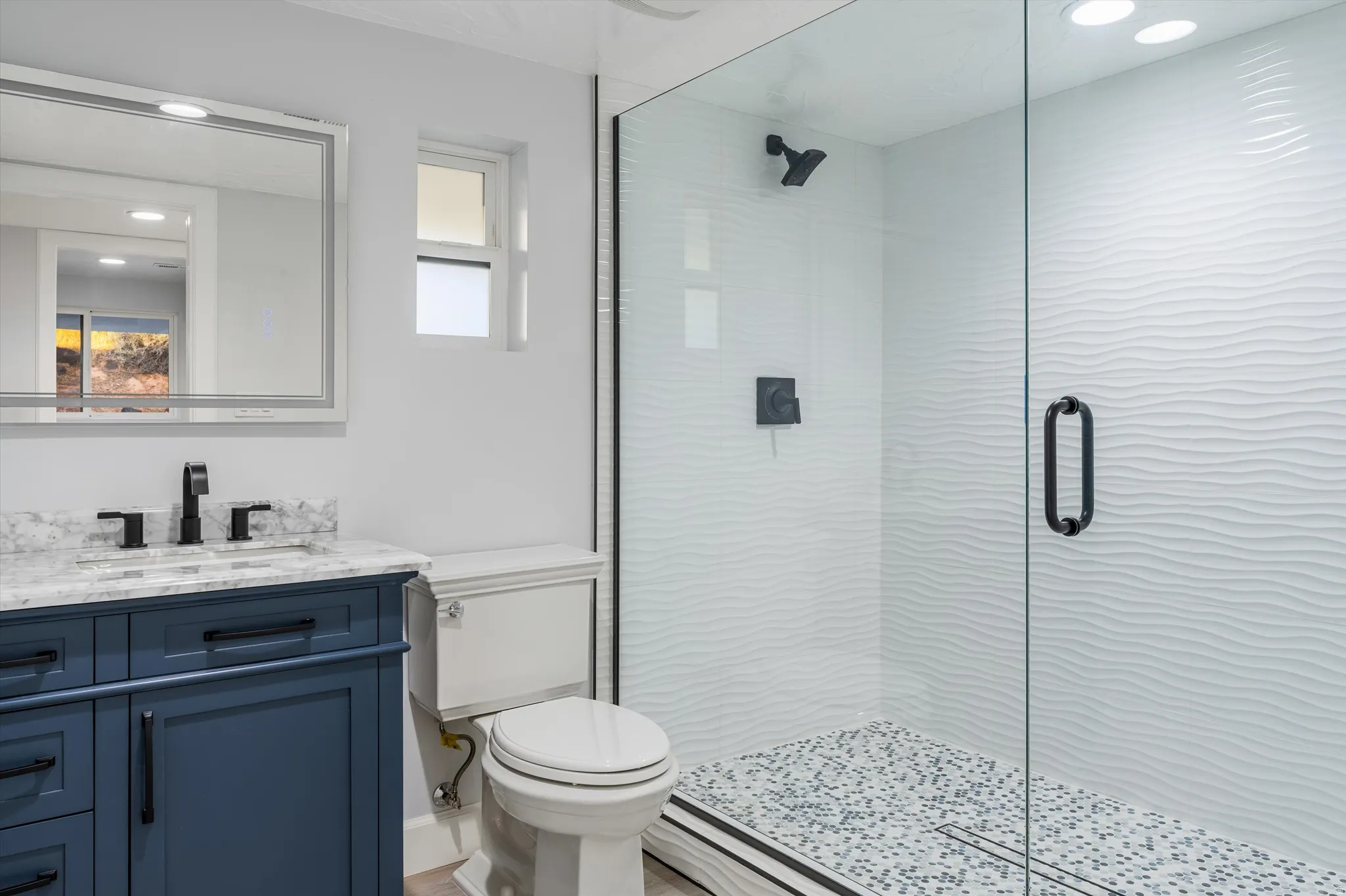 Glass-enclosed shower with a pebble-finish floor