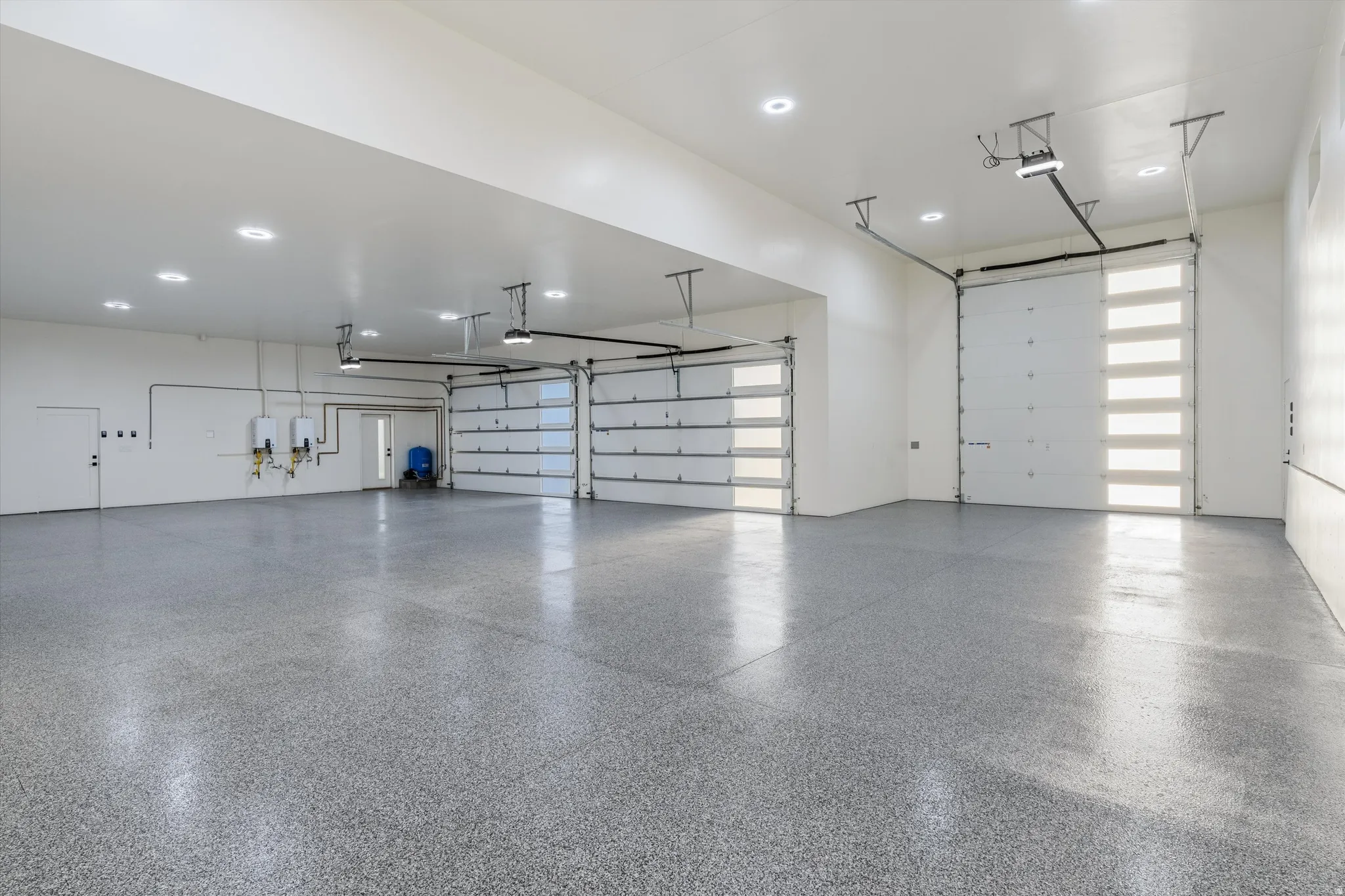 Spacious garage featuring a durable epoxy floor, multiple overhead doors, and recessed ceiling lighting