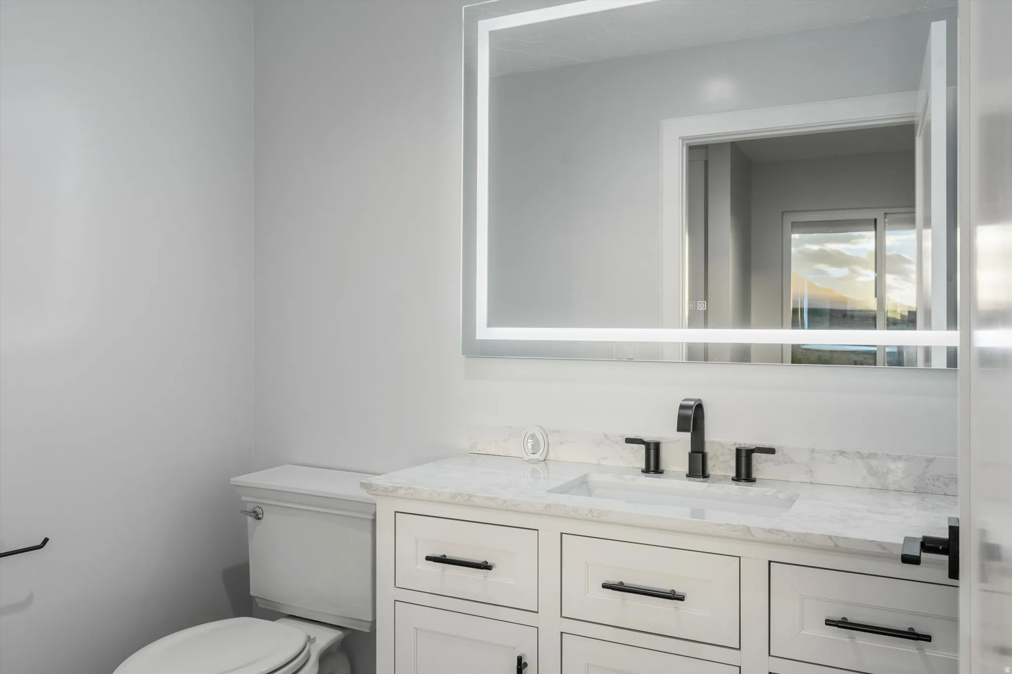 Bathroom vanity with white shaker-style cabinetry, a white countertop, and a built-in rectangular sink