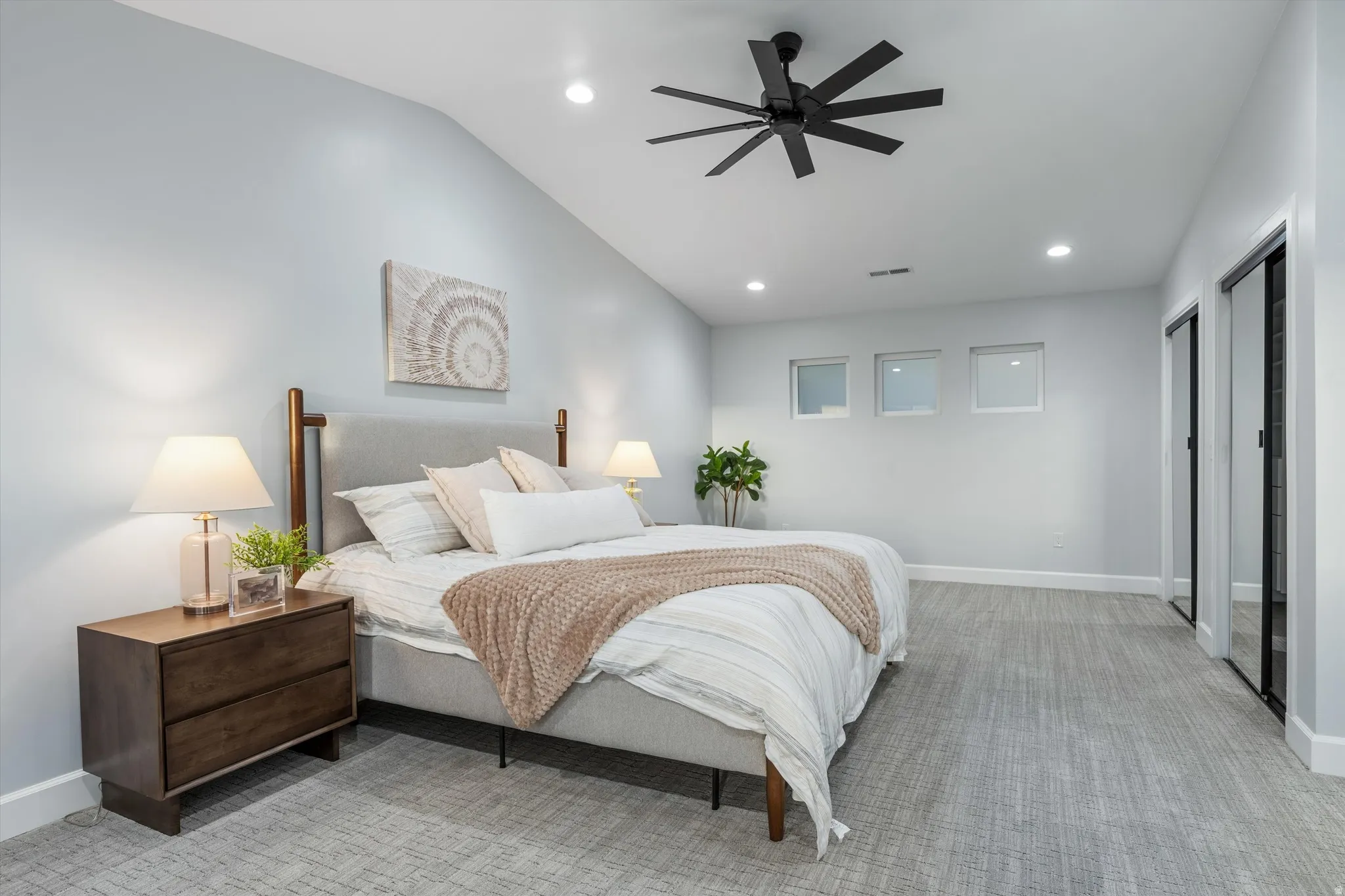 Vaulted ceiling with a black ceiling fan, recessed lighting, and three square windows