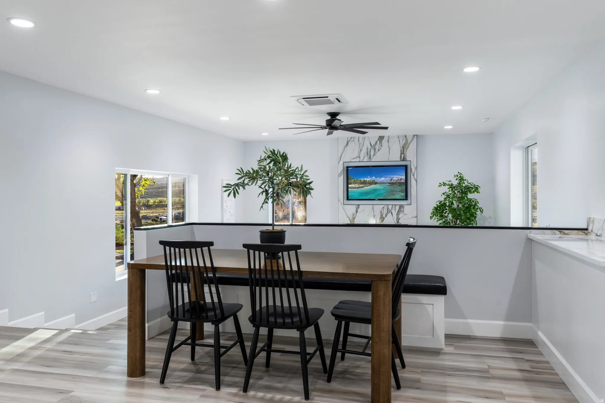 Recessed lighting, wood-finish flooring, half wall with cap, window, and ceiling fan