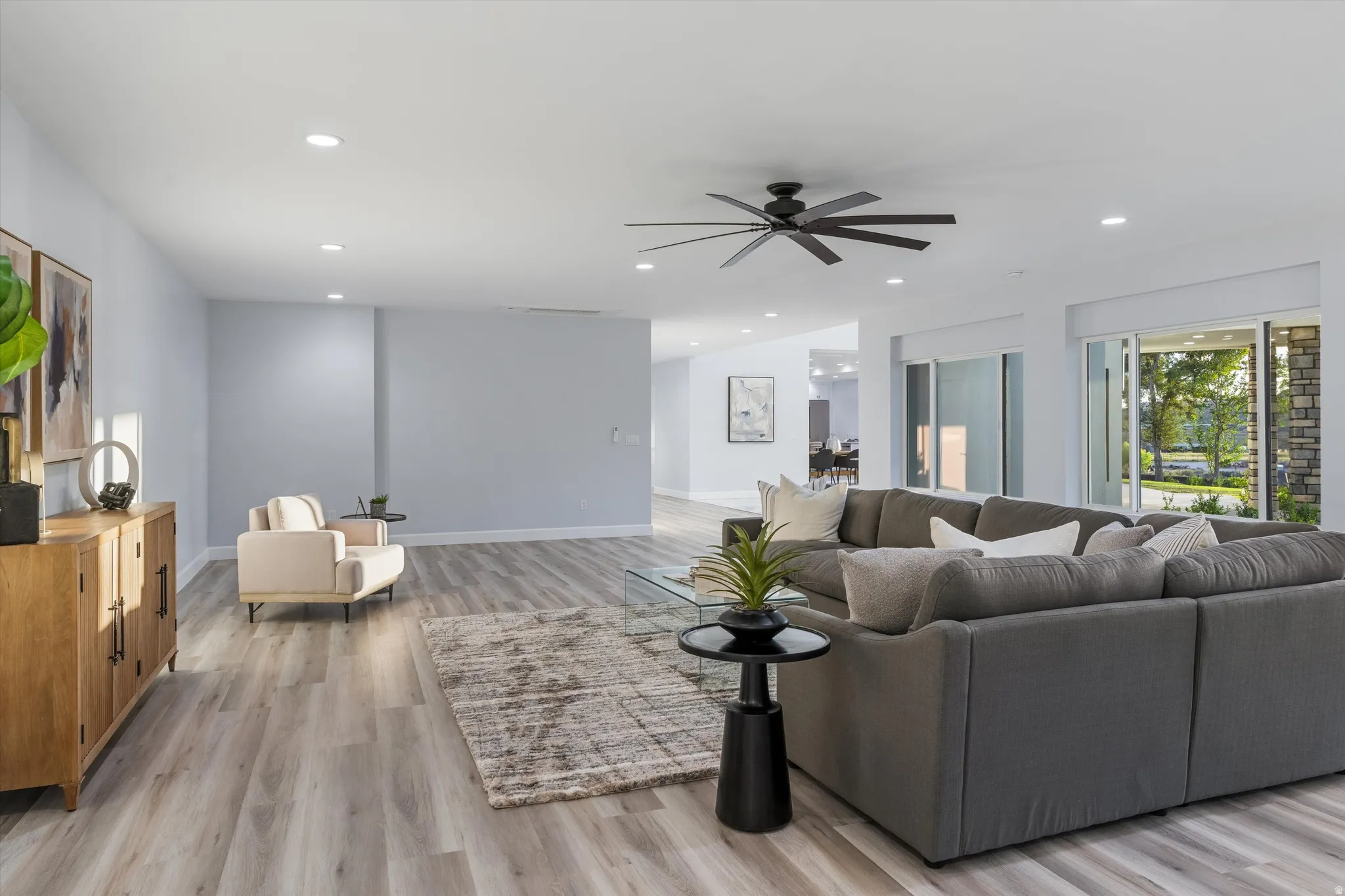 Spacious living area featuring light wood-finish flooring, recessed lighting, and a contemporary ceiling fan