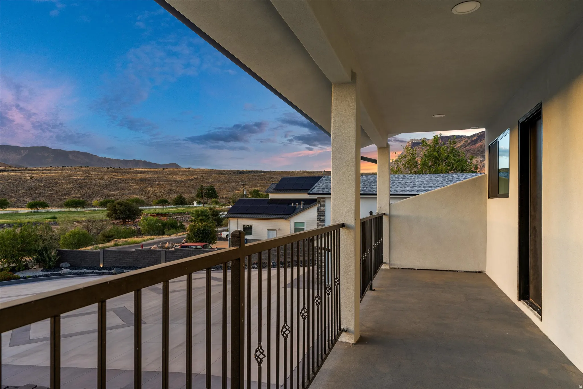 Covered balcony with decorative wrought iron railing, columns, and concrete flooring