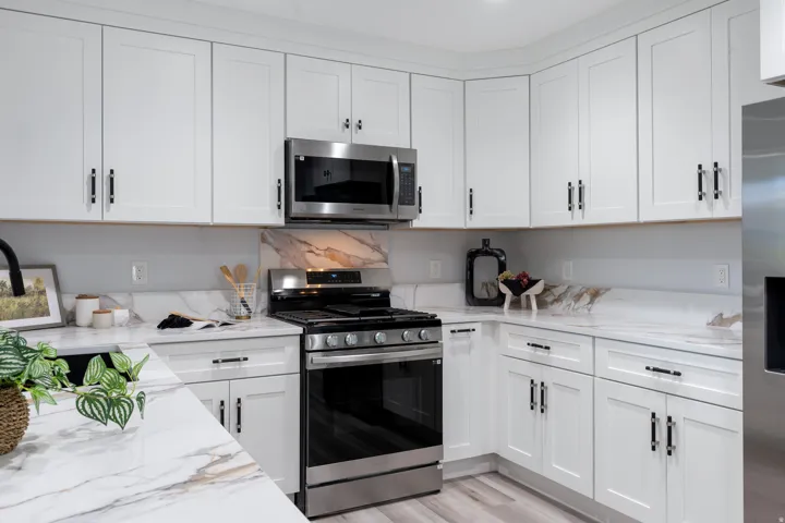 White shaker cabinetry with black hardware, stainless steel appliances, and marble-look countertops