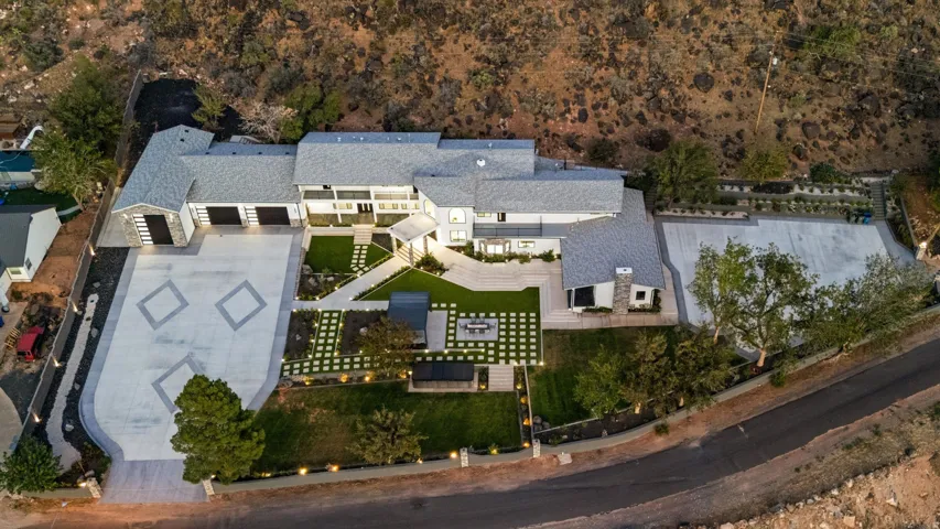 Expansive property featuring a multi-car garage, patterned concrete driveway, and a large front courtyard with integrated landscaping