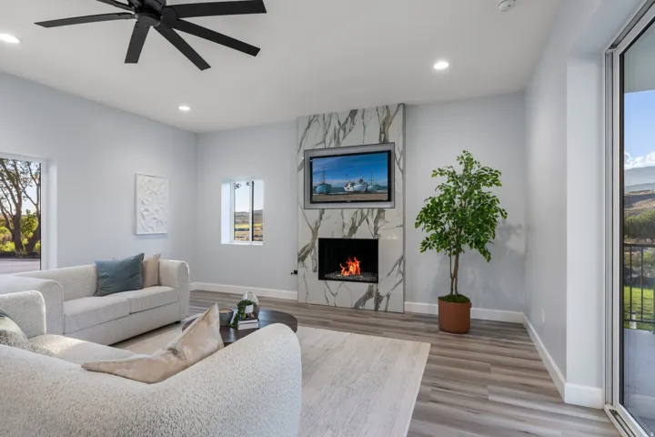 Modern fireplace with a natural stone surround, recessed lighting, wood-finish flooring, and a large sliding glass door