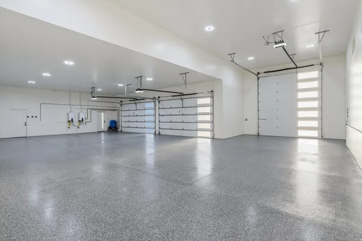Spacious garage featuring a durable epoxy floor, multiple overhead doors, and recessed ceiling lighting