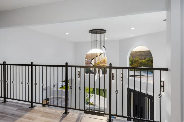 Open-concept upper level with an ornate wrought-iron railing and wood-finish flooring