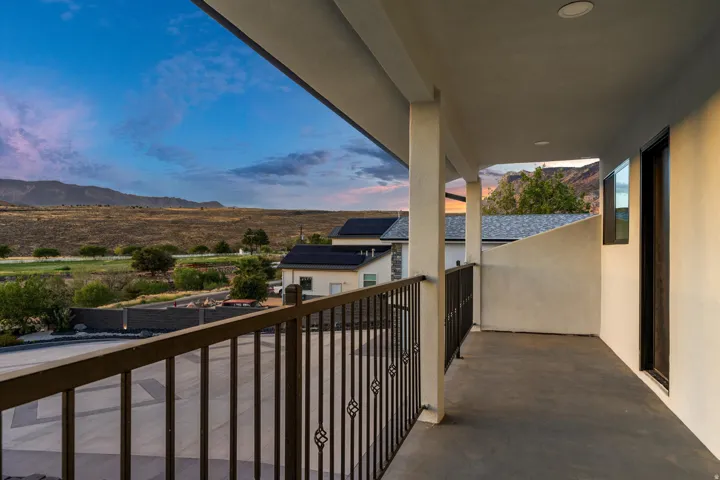 Covered balcony with decorative wrought iron railing, columns, and concrete flooring