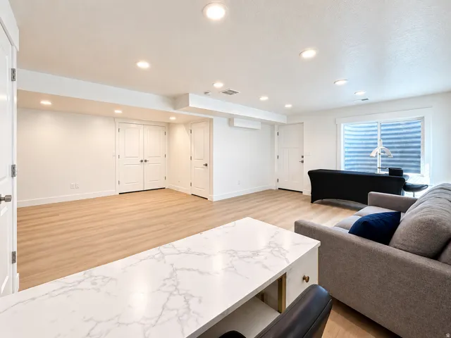 Recessed lighting, wood-finish flooring, white walls, double doors, and a window well