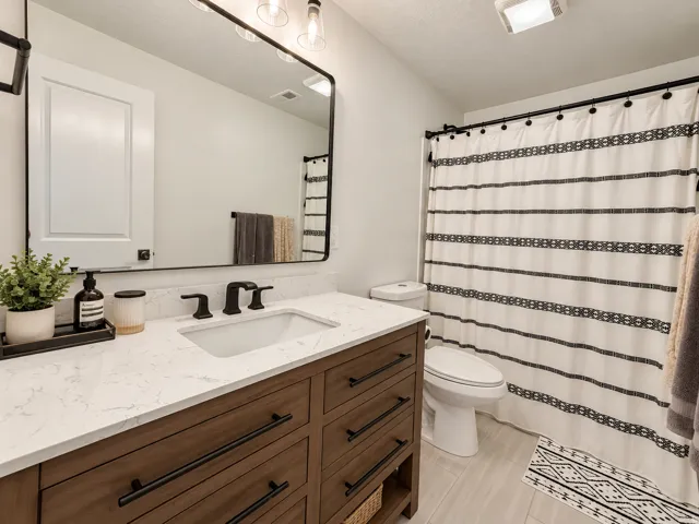 Wood-finish vanity with drawer storage, white countertop, rectangular undermount sink, and matte black fixtures