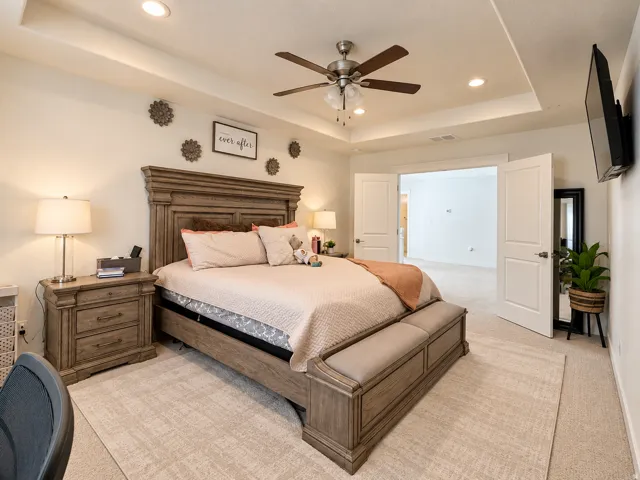 Tray ceiling with recessed lighting, ceiling fan, carpeted flooring, and double doors opening to an additional room