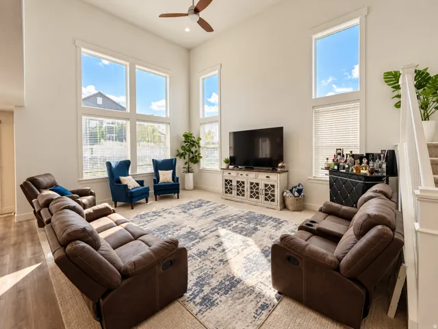Double-height ceilings with a ceiling fan, abundant natural light from tall windows, and light-toned walls