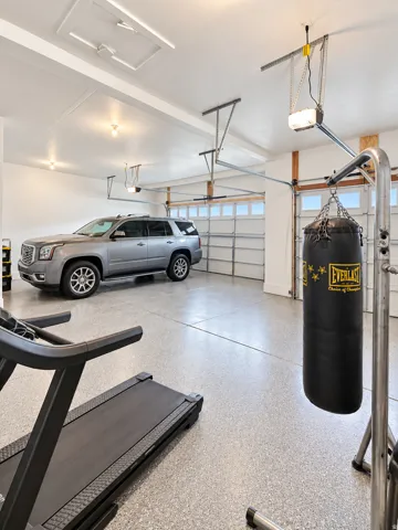 Spacious garage featuring a durable epoxy floor coating, multiple garage doors with automatic openers, recessed lighting, and a white finished ceiling
