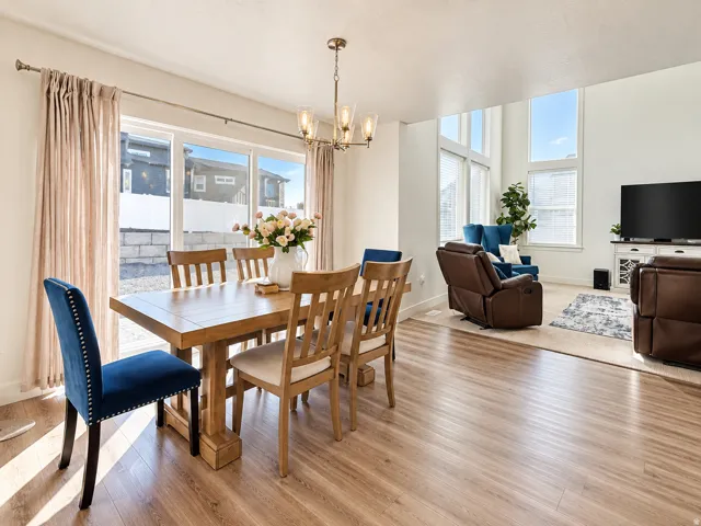 Open-concept living space featuring wood-finish flooring, ample natural light from large windows, and a modern chandelier
