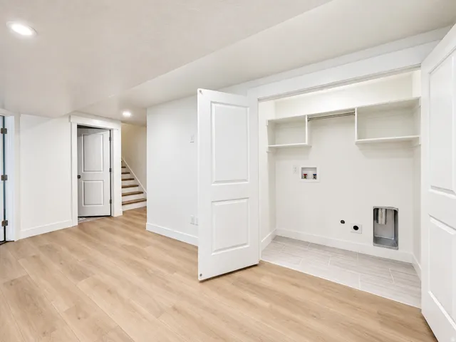 Laundry closet with built-in shelving, tile flooring, and light wood-finish flooring