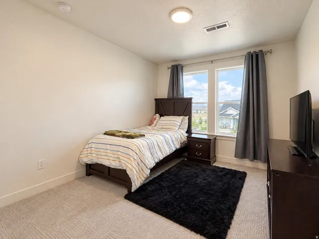 Recessed ceiling light, two windows with white trim, light-colored carpet flooring, and white painted walls