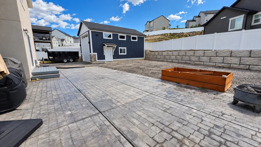 Spacious paver patio with a detached auxiliary building featuring a garage door and side entry