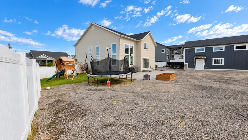 Rear exterior featuring a patio, multiple windows, and a white privacy fence
