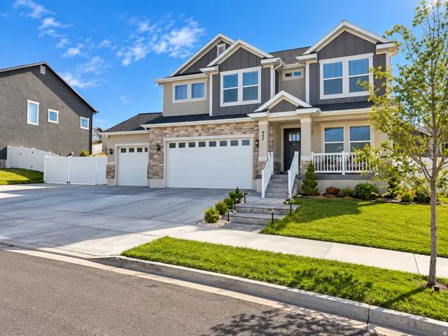 Stone and siding exterior with a covered porch, two-car garage, and concrete driveway