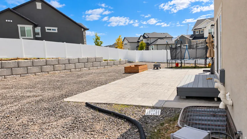 Rear patio with paver stone surface, adjacent composite decking, and a retaining wall