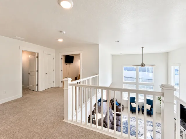 Upper level landing with carpeted flooring, white baluster railing, and recessed lighting