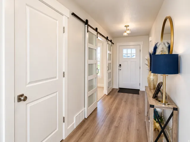 Wood-finish flooring throughout, white interior doors with brushed nickel hardware, and a white front entry door with glass inserts