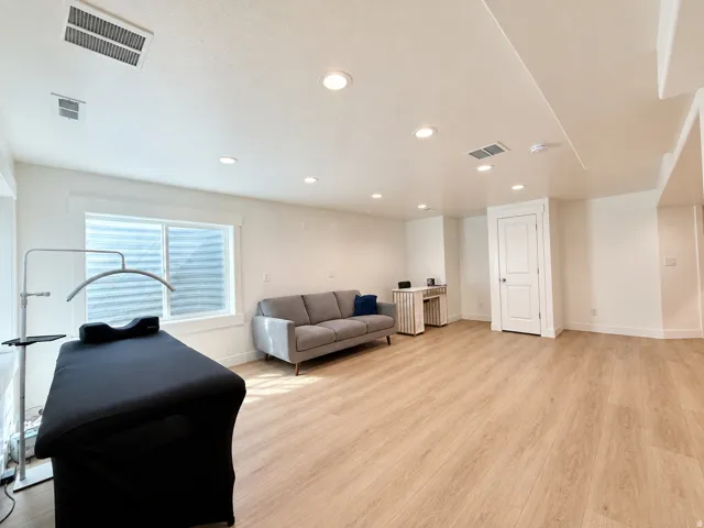 Spacious room featuring light wood-finish flooring, recessed lighting, white walls, and a window with white trim