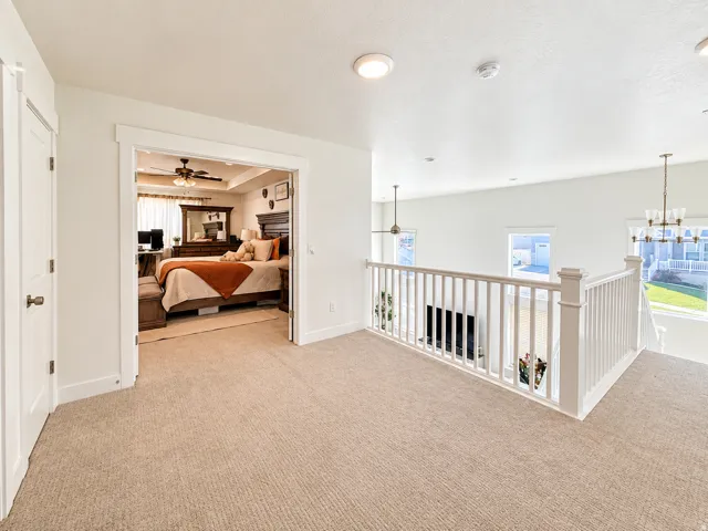 Carpeted loft space with white railing, recessed lighting, and a view into a lower level with a fireplace