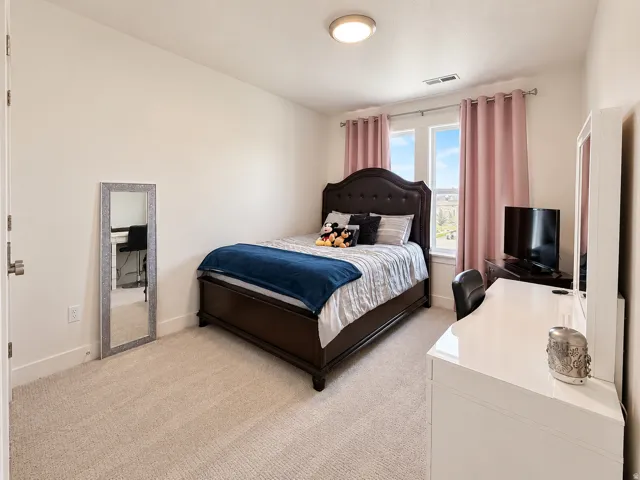 Carpeted bedroom with a double window, overhead flush-mount lighting, and light-toned walls