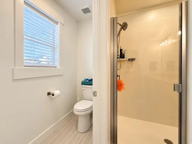 Glass-enclosed shower with a handheld showerhead and built-in shelving