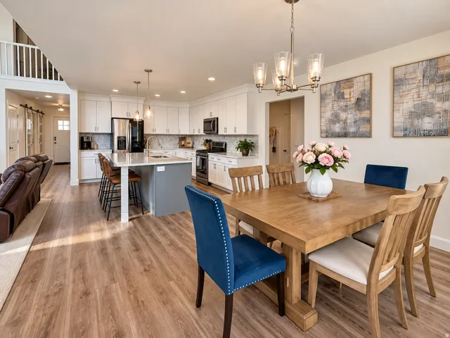 Open-concept living space featuring wood-finish flooring, a kitchen island with seating, a white subway tile backsplash, and stainless steel appliances
