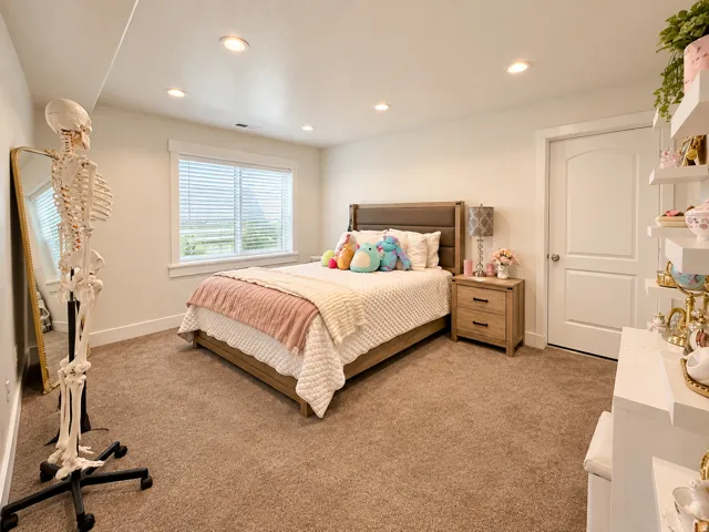 Recessed lighting, window with blinds, carpet flooring, flat panel door with arched top, and built-in shelving
