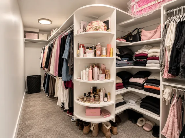 Built-in shelving with hanging rods, integrated corner shelving, recessed lighting, and carpet flooring